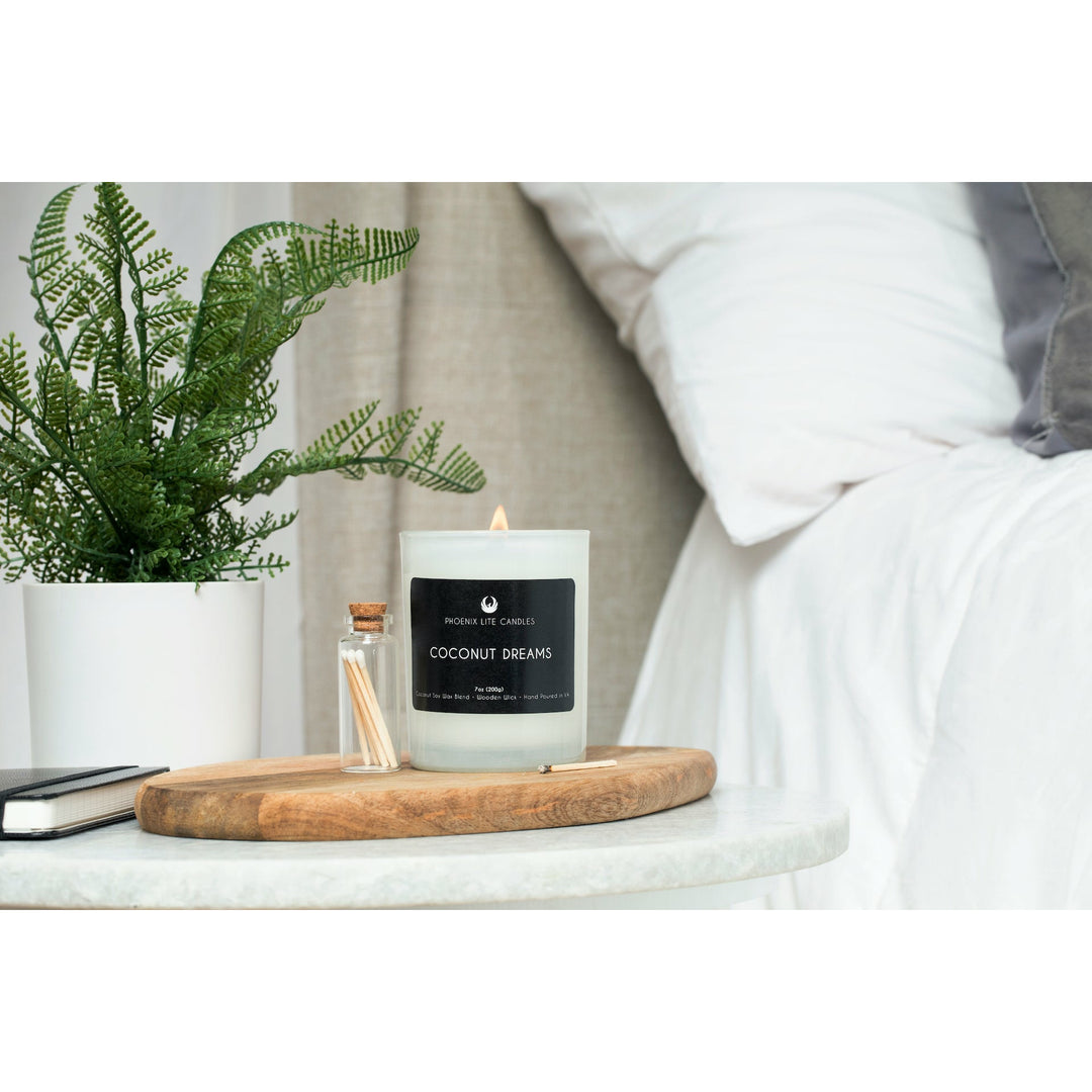 A photo of a lit seven ounce candle in a white jar labeled coconut dreams